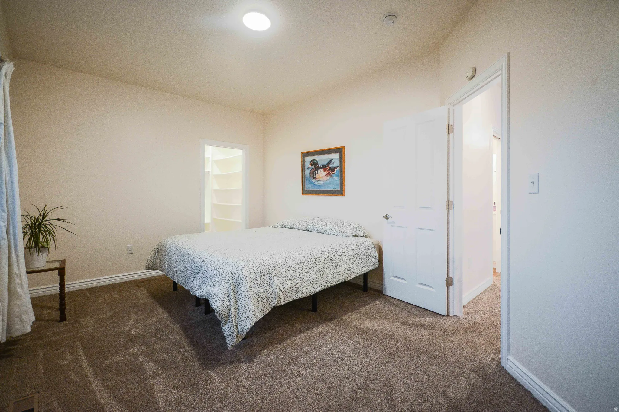 Carpeted room featuring a neutral color palette, a vaulted ceiling, and an integrated ceiling light fixture