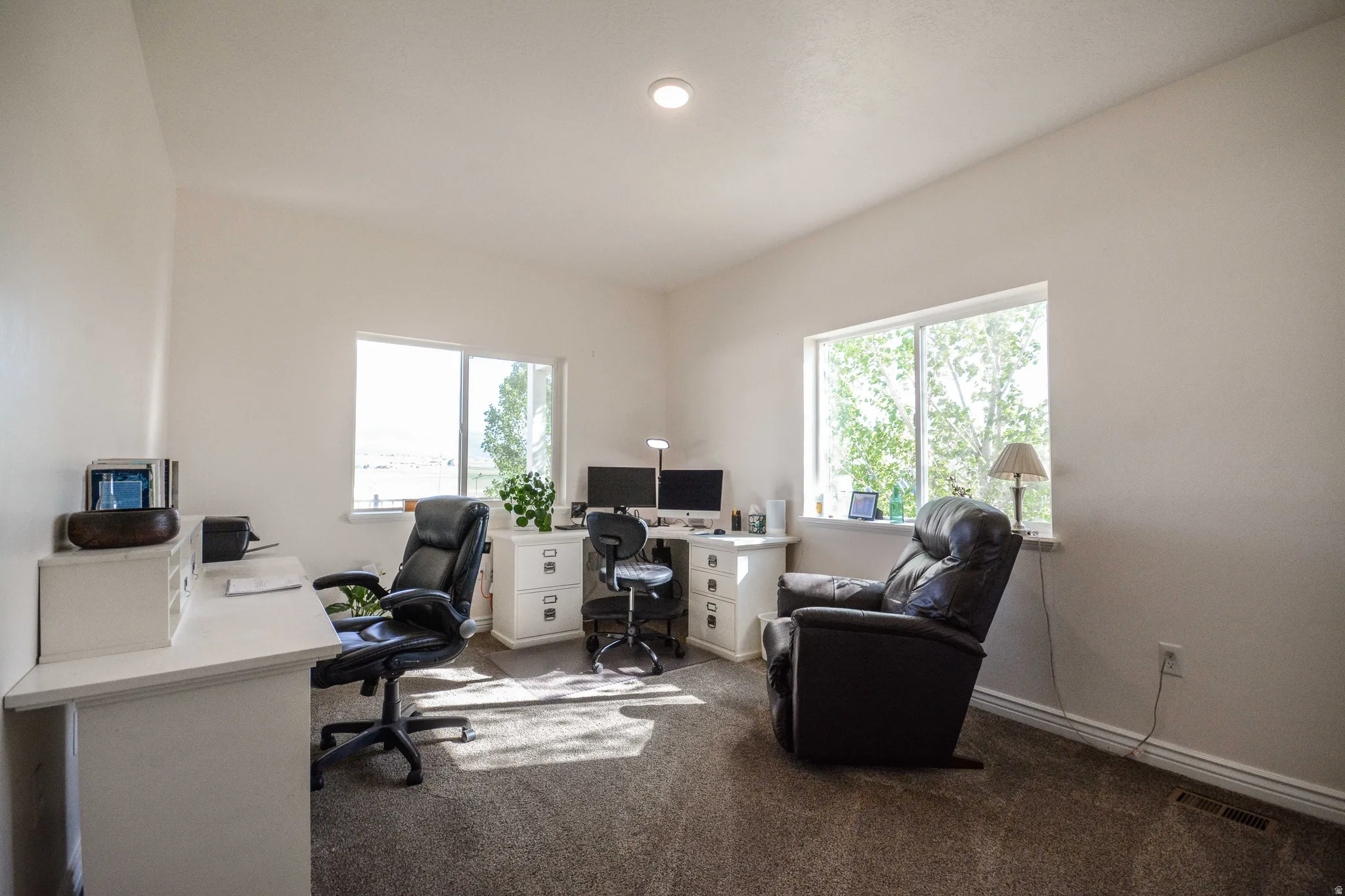 Spacious room featuring neutral-toned walls, recessed lighting, and two large windows offering abundant natural light
