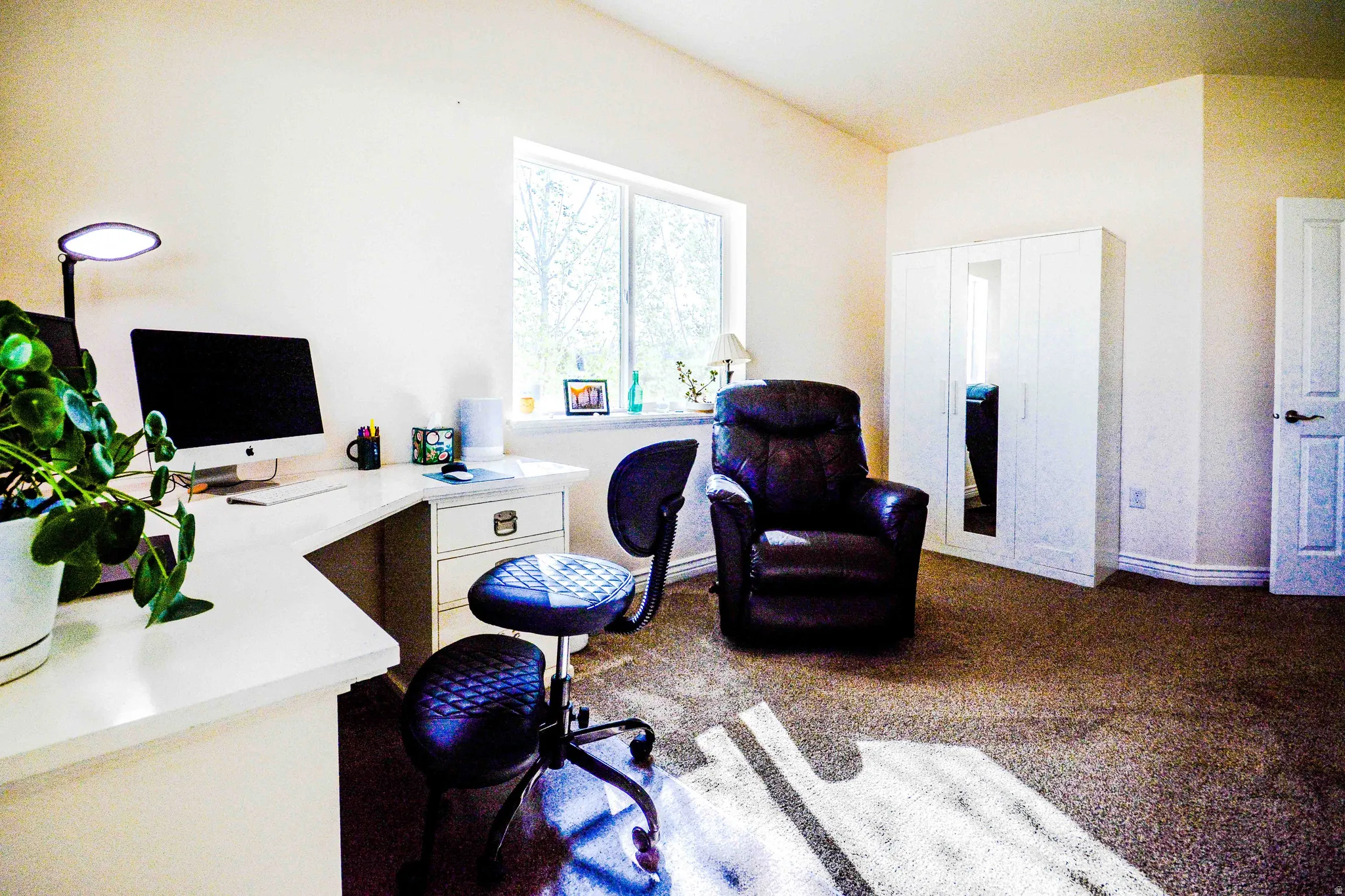 Room featuring a corner desk with storage drawers, a window with exterior views, and carpet flooring