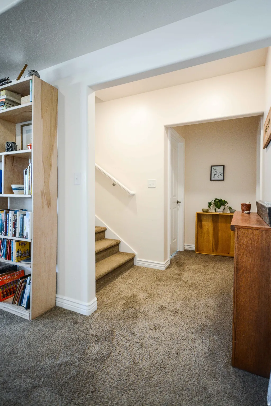 Carpeted flooring throughout, featuring a staircase with carpeted treads and a white handrail
