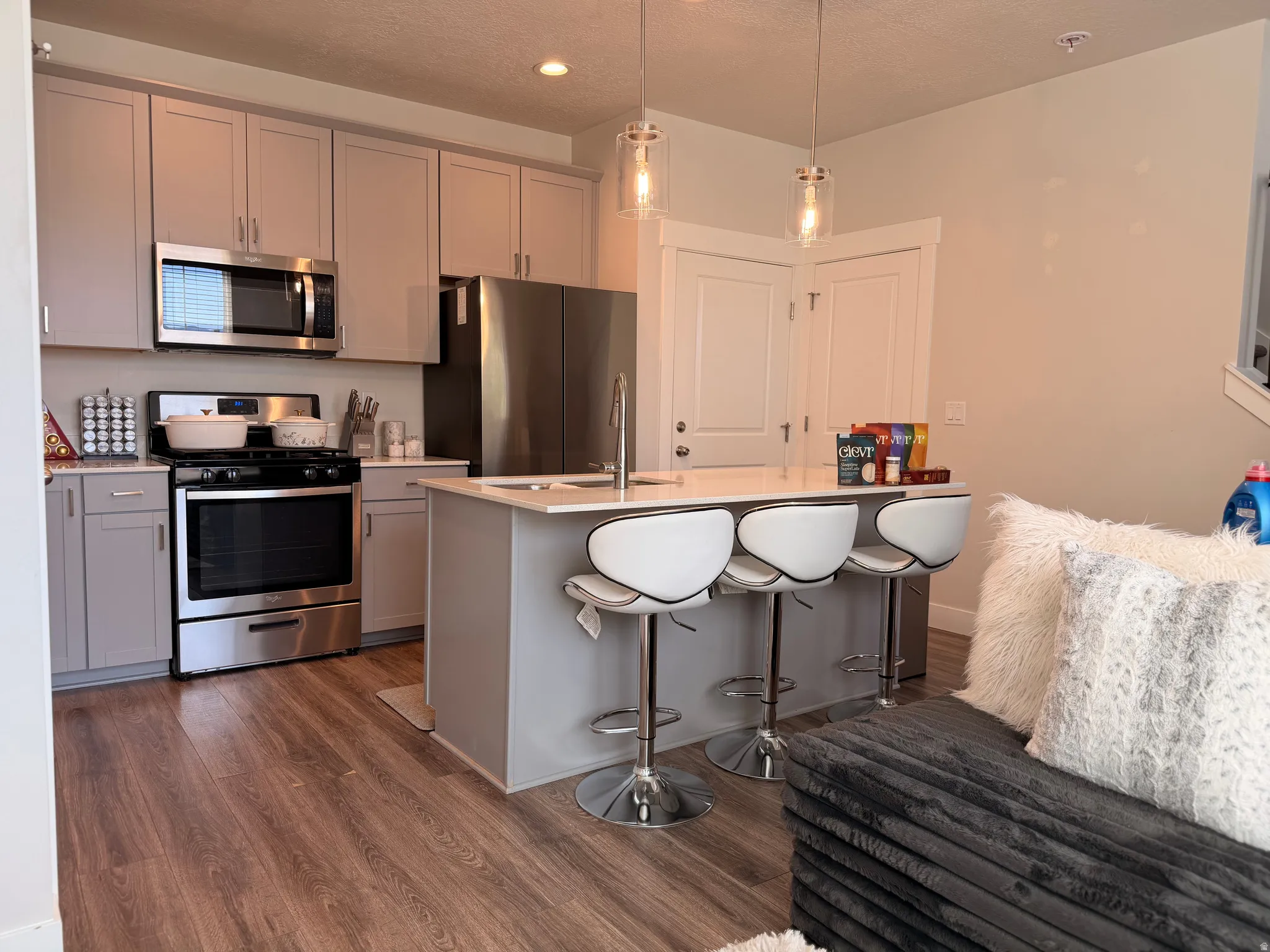 Modern kitchen featuring stainless steel appliances, light gray cabinetry, and wood-finish flooring