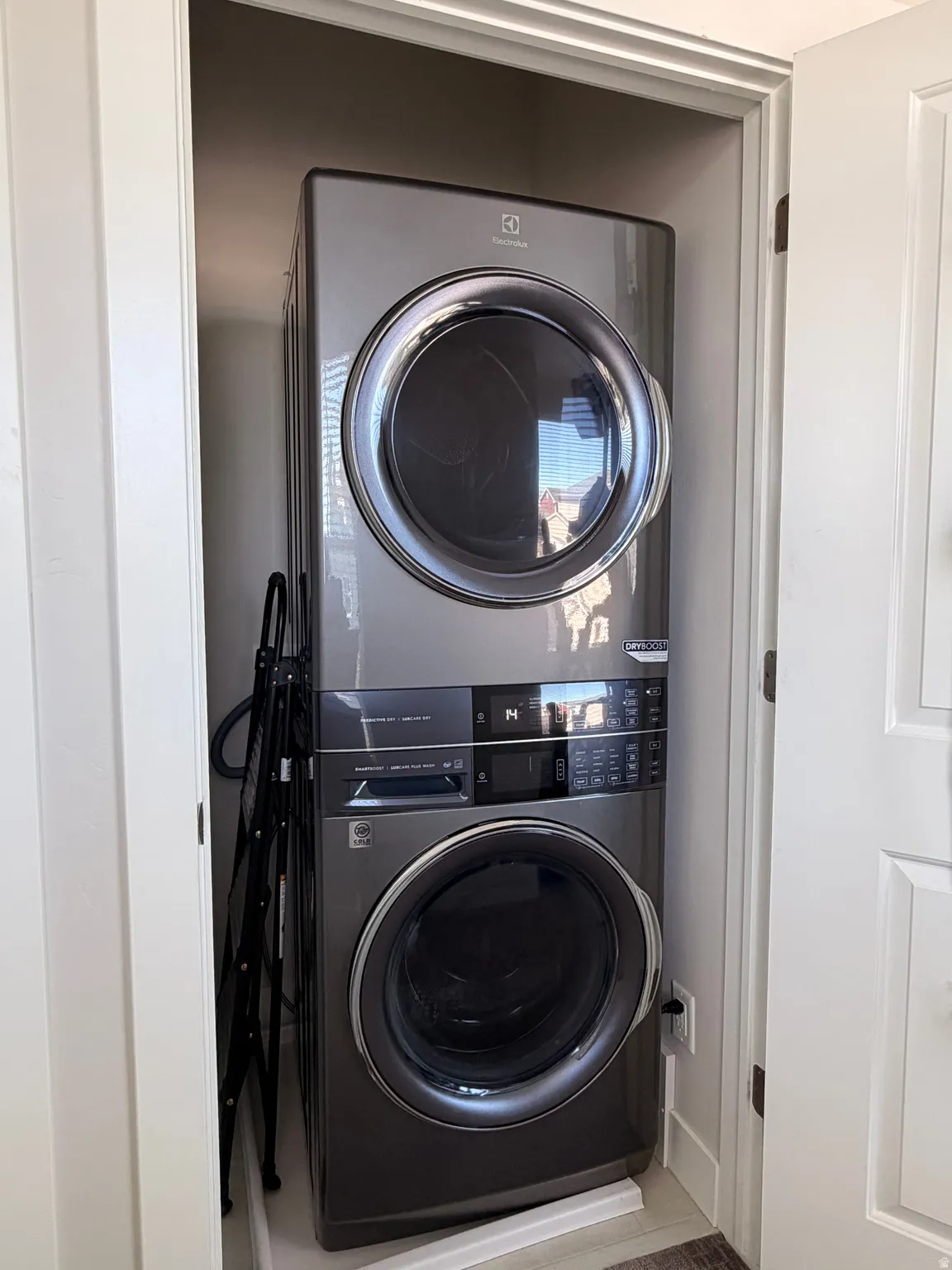 Dedicated laundry alcove featuring a stacked washer and dryer unit, front-loading design, control panel, and neutral wall tones