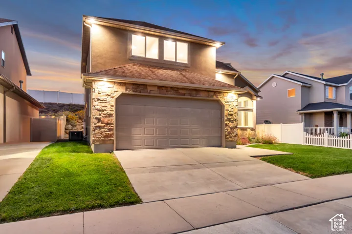Stucco exterior with stone accenting, an attached two-car garage, and a concrete driveway