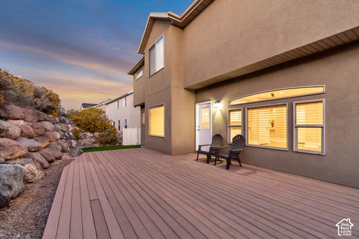 Expansive composite decking with a curved edge, stucco exterior, and multi-pane windows