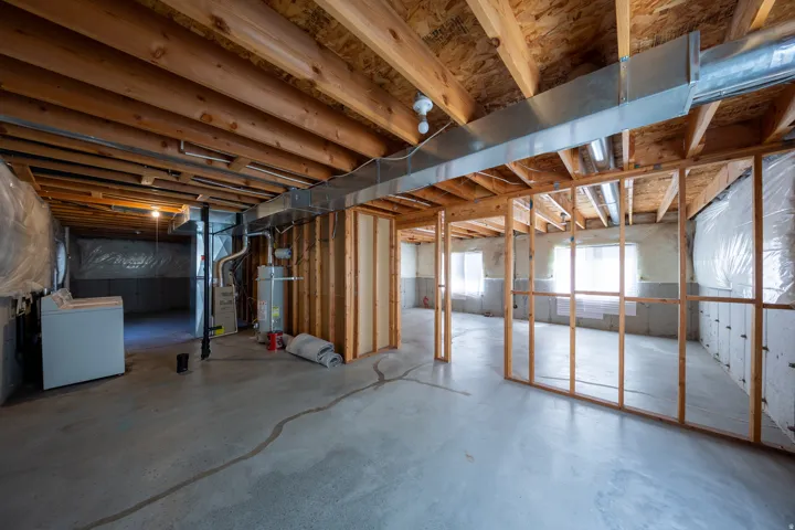Unfinished basement with exposed ceiling joists and concrete flooring