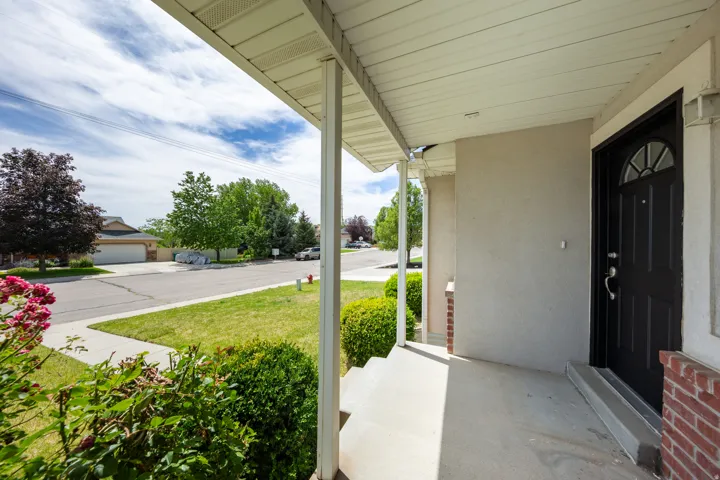 Covered front porch with concrete flooring and a dark paneled entry door with an arched transom