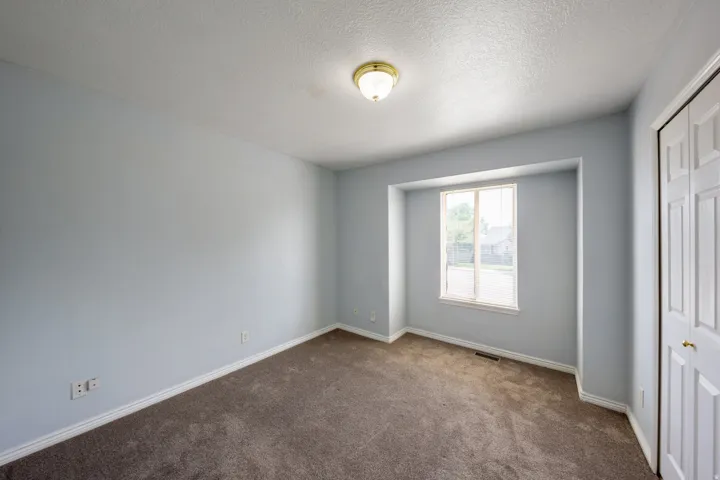 Room featuring light blue walls, brown carpet flooring, and white baseboards