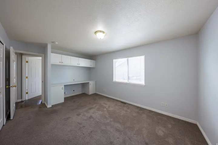 Room with built-in desk cabinetry and overhead storage