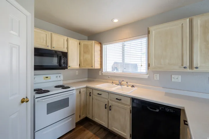 Kitchen with wood-finish flooring, light-toned cabinetry, and white countertops