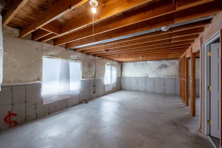 Unfinished basement space featuring exposed wood joists and concrete flooring