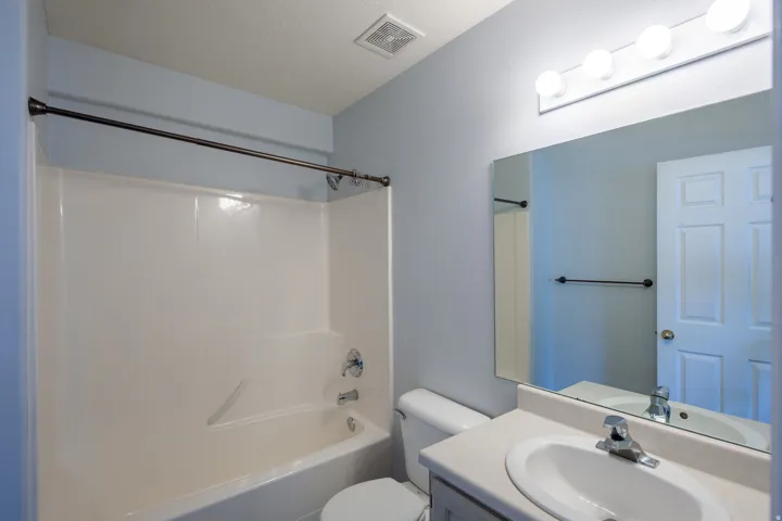 Bathroom featuring a shower-tub combination with a white surround, single-handle faucet, and bronze-finish shower rod