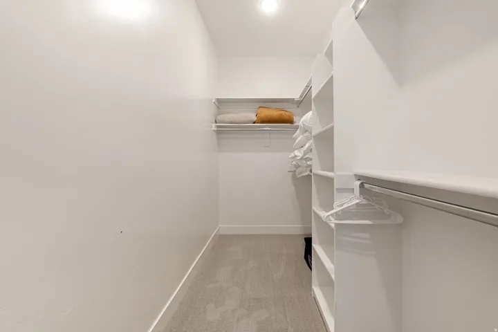 Walk-in closet featuring built-in shelving, hanging rods, and recessed lighting