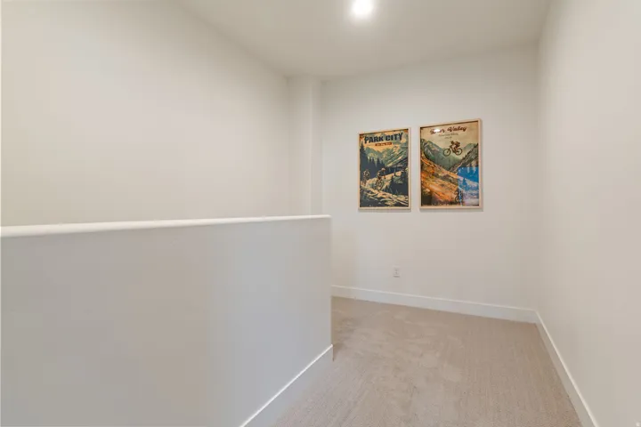 Carpeted hallway featuring a white half-wall and contemporary baseboards