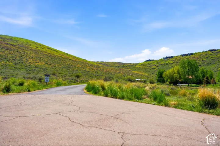Paved road extending through rolling hills with vibrant green vegetation