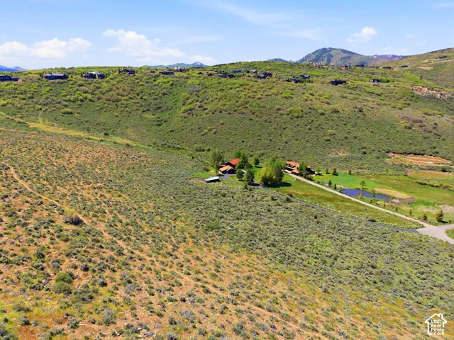 Expansive natural landscape featuring a private residence, additional outbuildings, a visible pond, and a long driveway