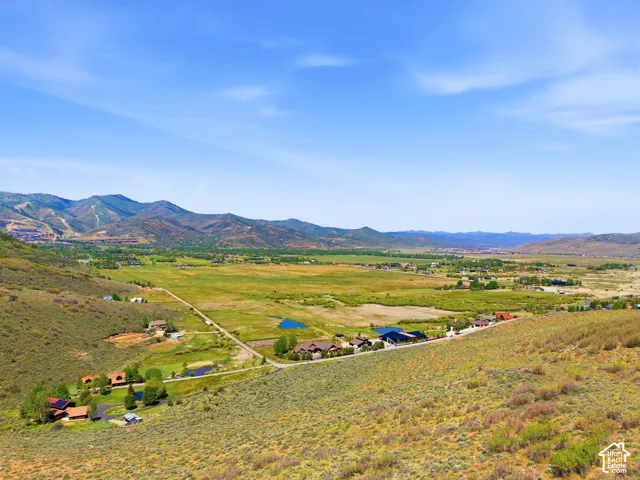 Expansive valley landscape featuring distant mountain ranges and scattered residential properties