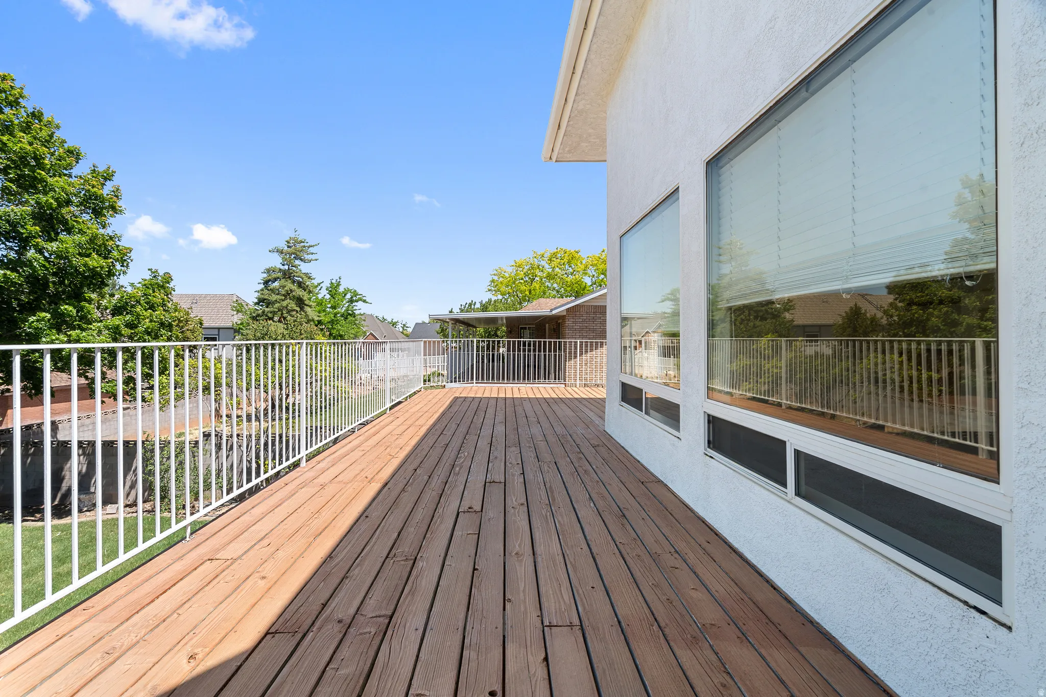Expansive outdoor deck featuring wood plank flooring and white metal railing