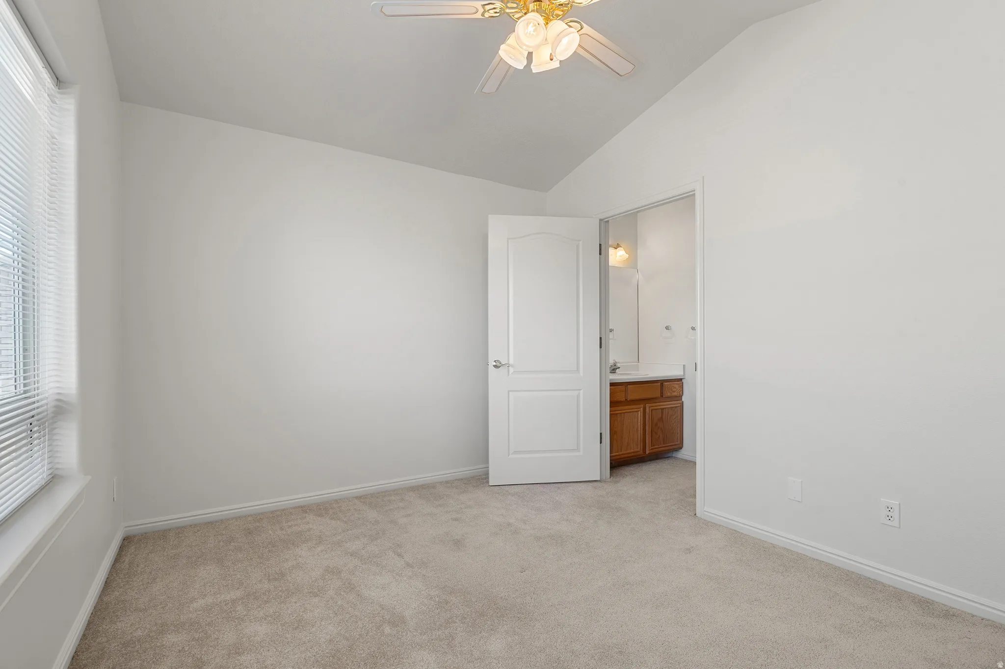 Carpeted room featuring a vaulted ceiling and a ceiling fan with integrated lighting