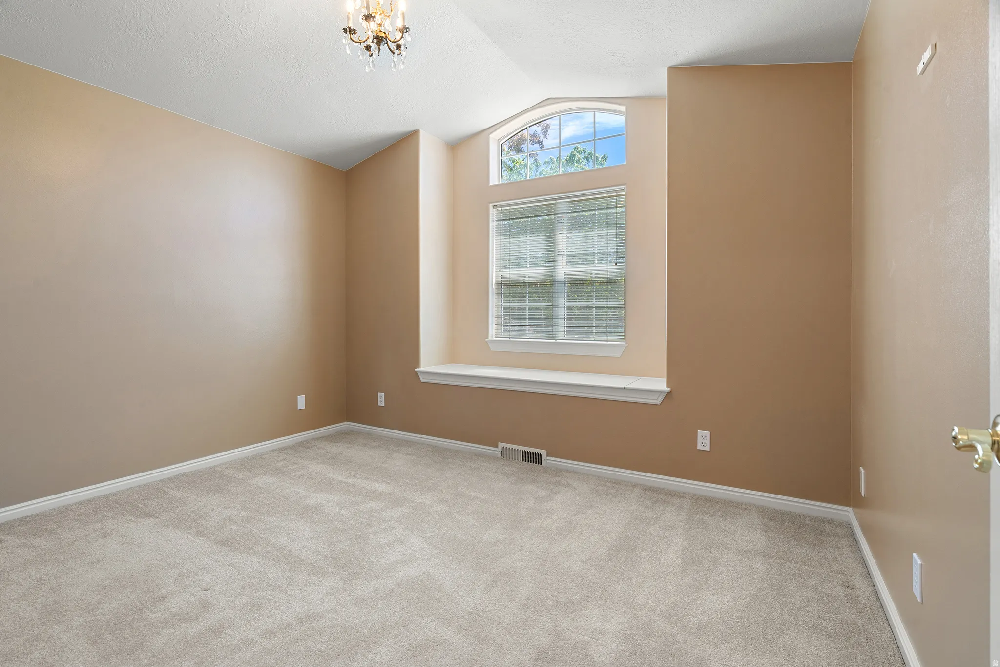 Carpeted room featuring a large arched window with horizontal blinds and a window sill