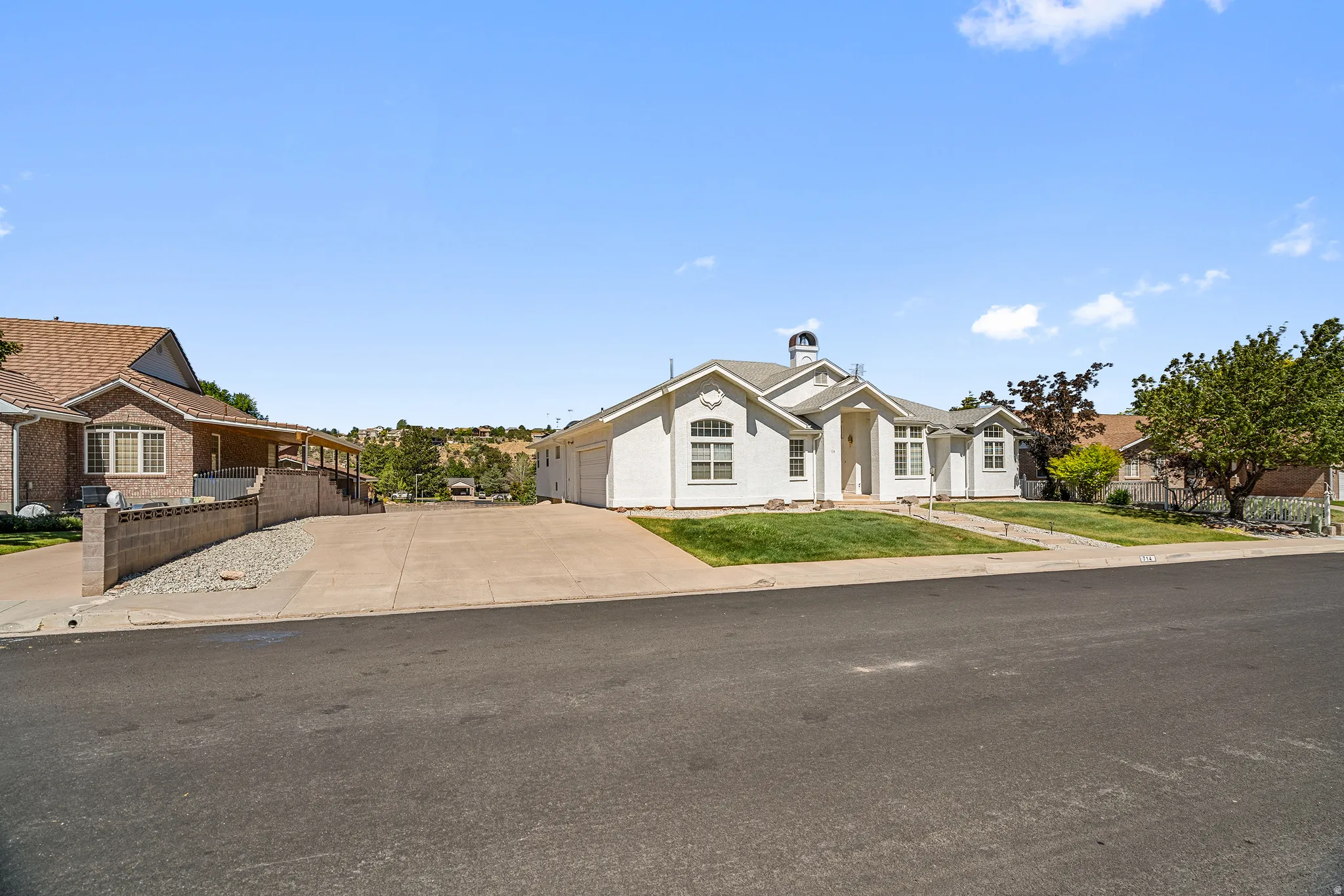 White exterior with an arched entryway, gabled roofline, and front landscaping