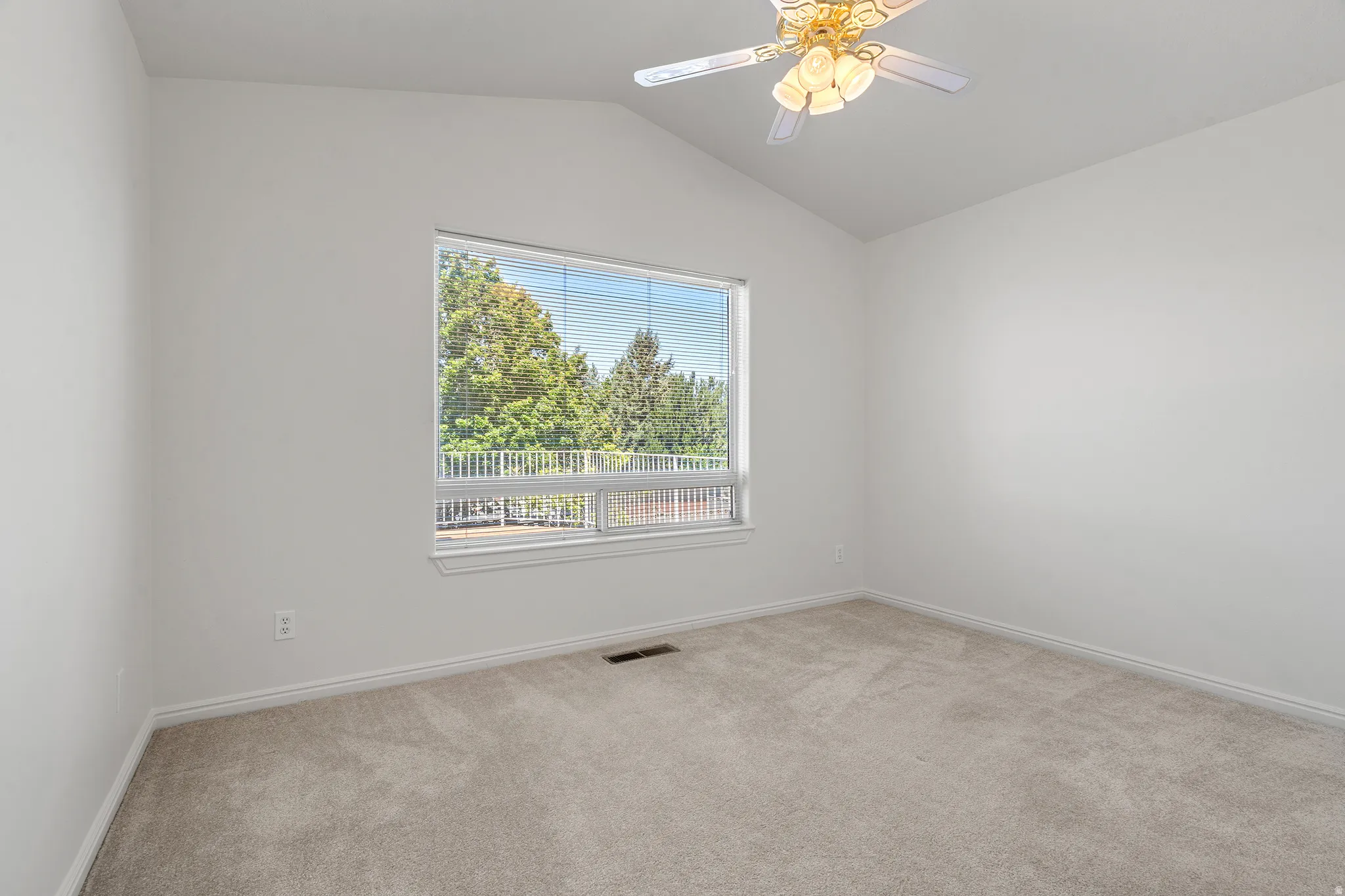 Room featuring a vaulted ceiling with a decorative ceiling fan, light gray carpeting, and white baseboards