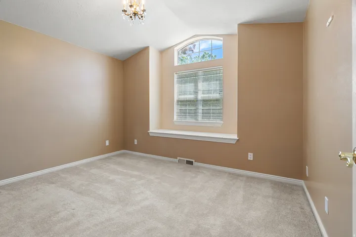 Carpeted room featuring a large arched window with horizontal blinds and a window sill