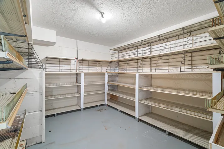 Spacious storage area featuring extensive built-in shelving, durable wire racks, and a concrete floor