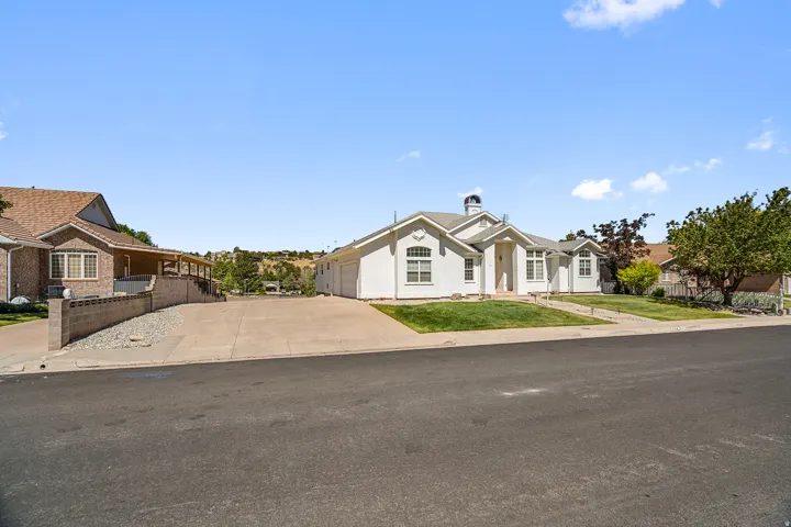 White exterior with an arched entryway, gabled roofline, and front landscaping