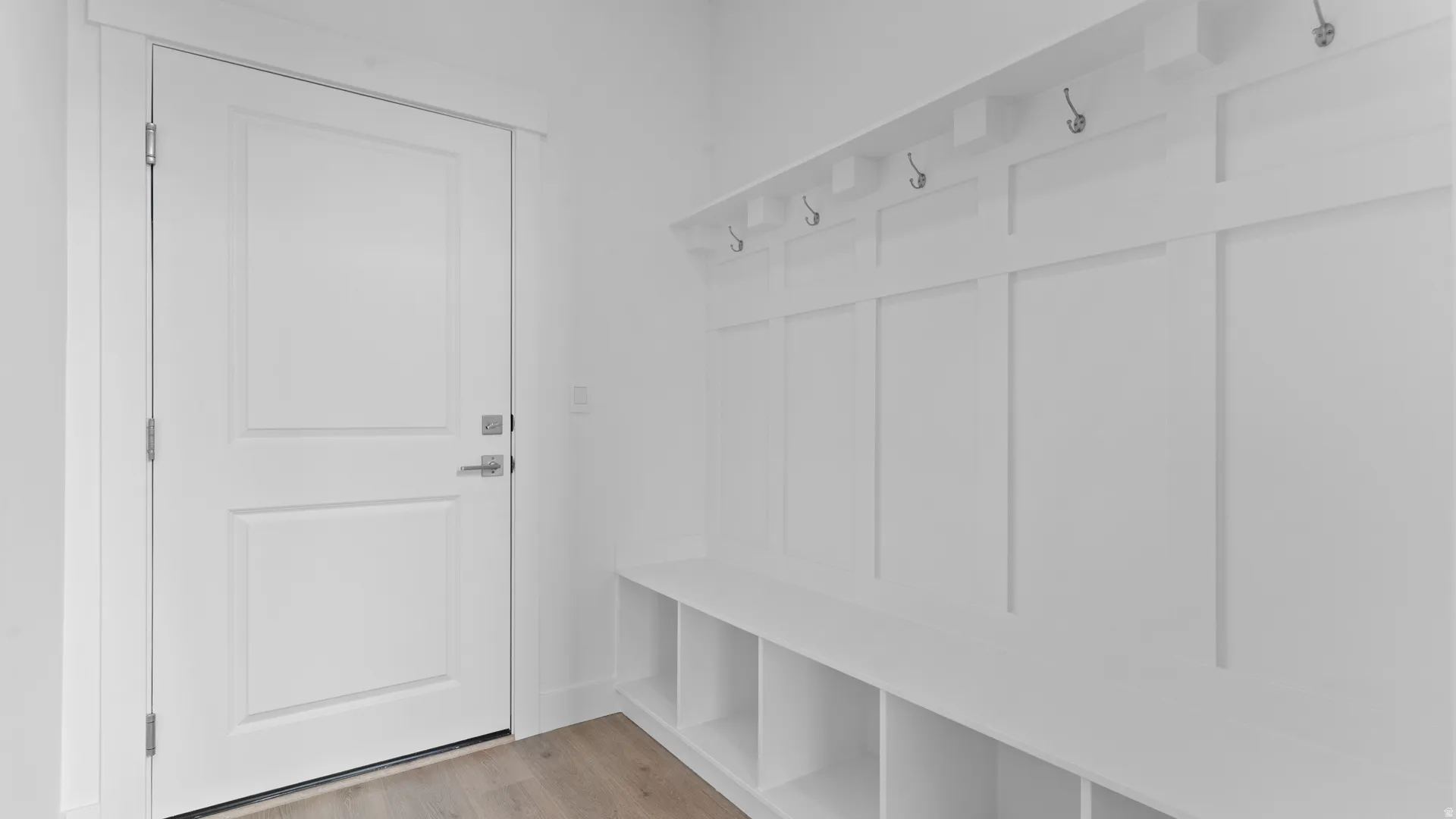 Mudroom featuring white board and batten paneling, built-in bench with cubbies, and integrated coat hooks