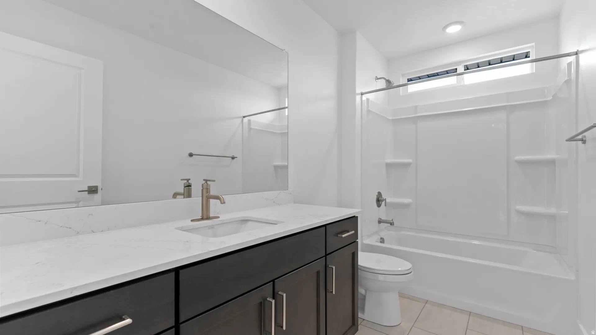 Bathroom featuring a dark wood-finish vanity with a white countertop and undermount sink, a large mirror, and a white bathtub with an overhead window