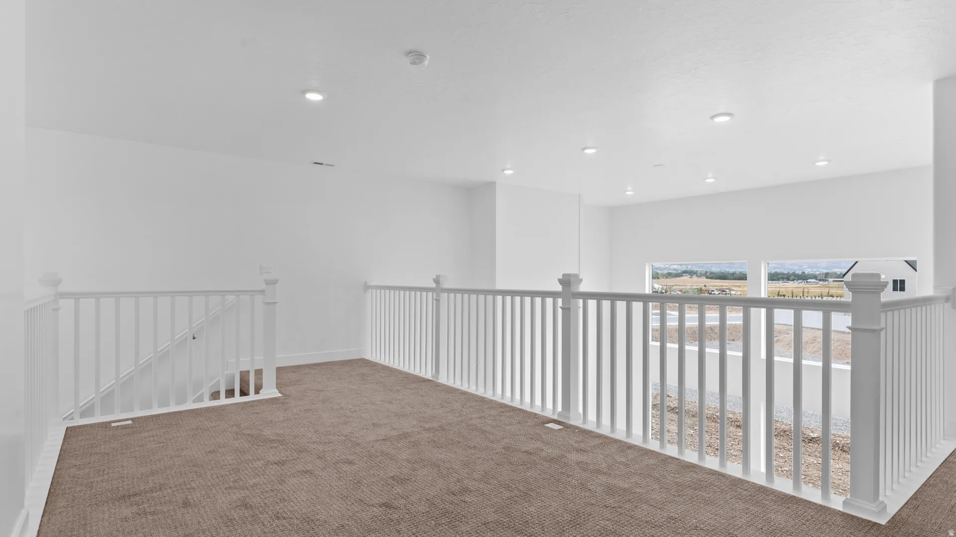 Expansive open loft area featuring plush brown carpeting and white railing