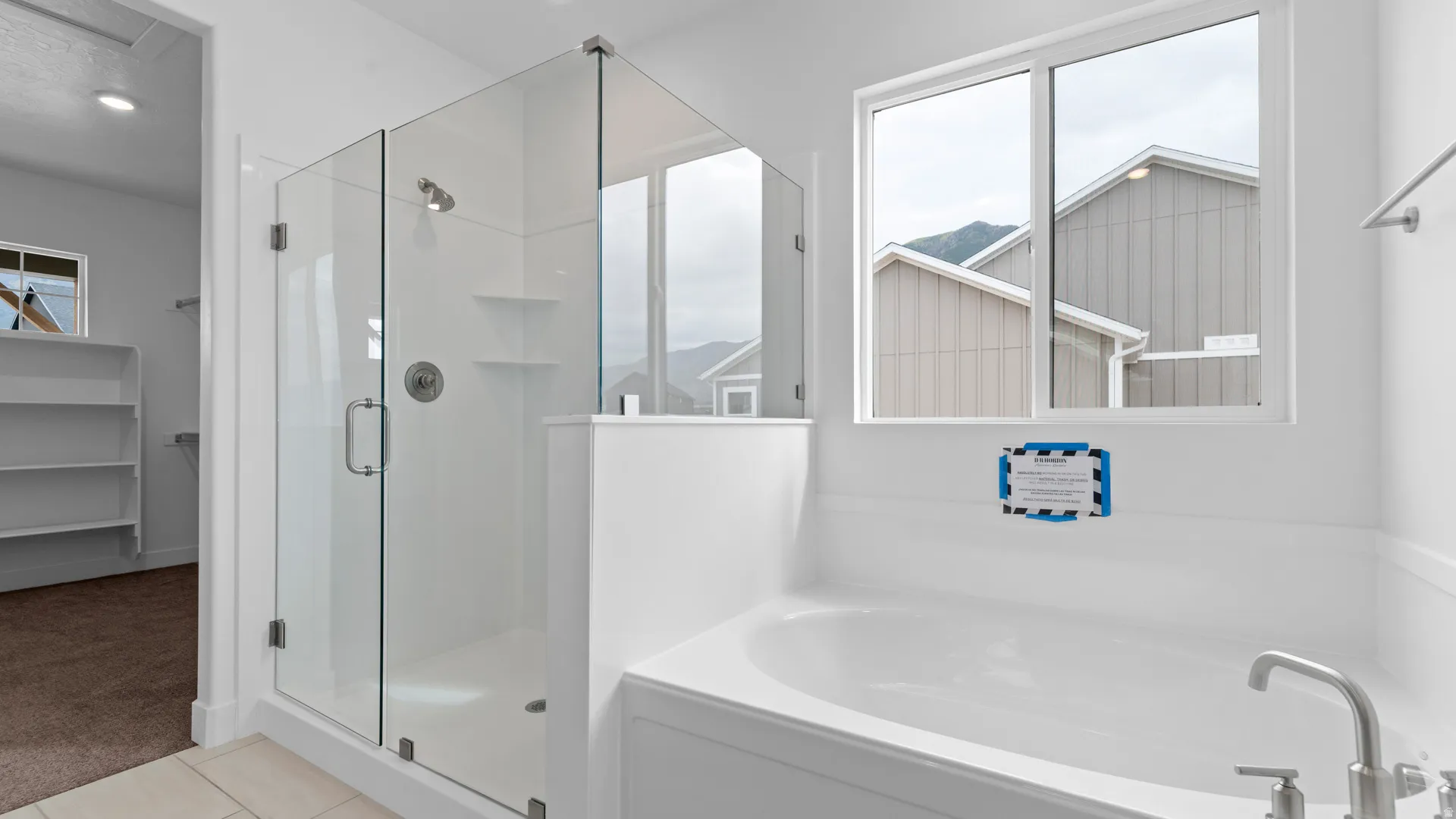 Bathroom featuring a glass-enclosed shower, built-in soaking tub, and a window providing natural light