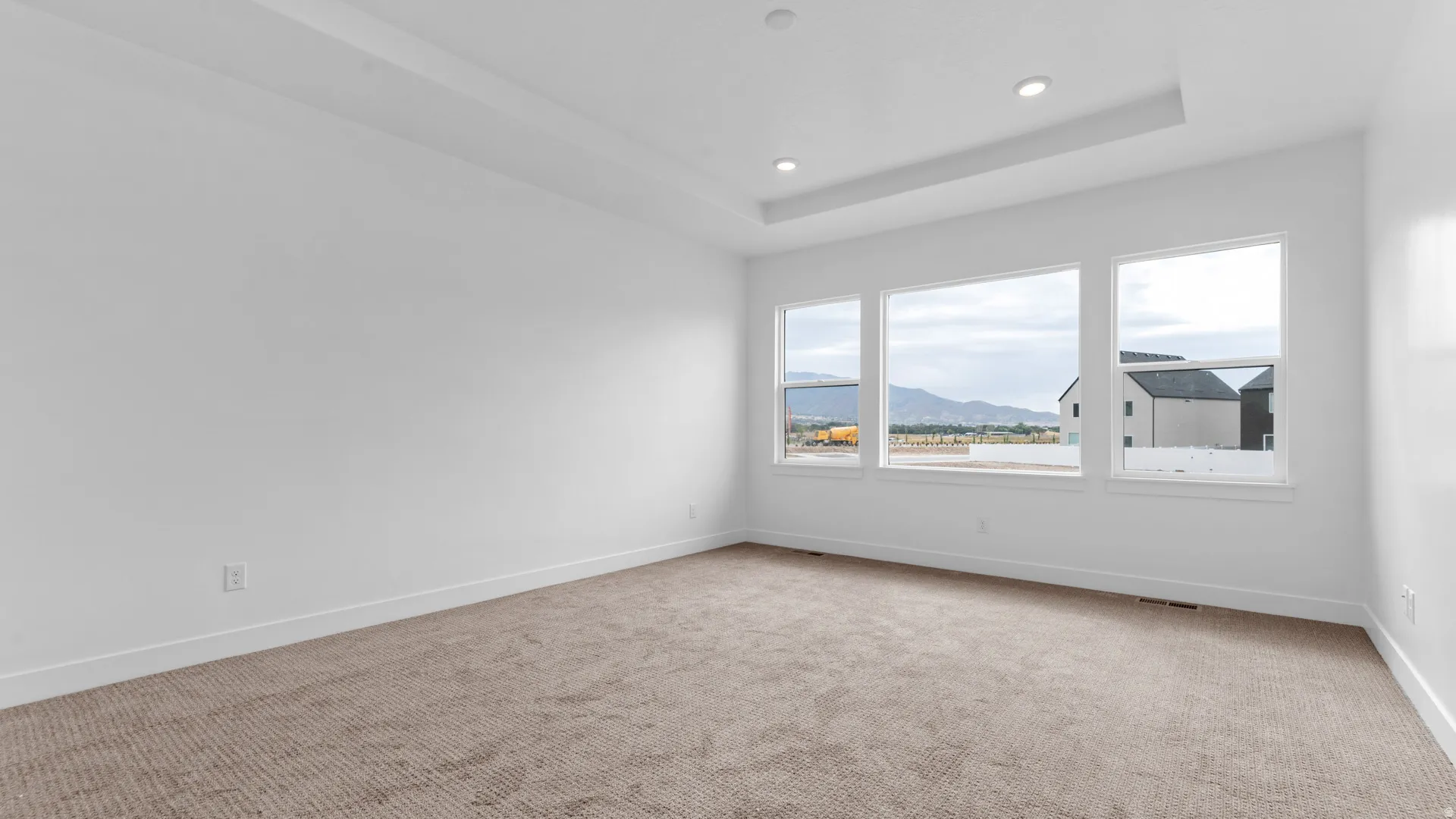 Spacious interior room featuring a tray ceiling with recessed lighting
