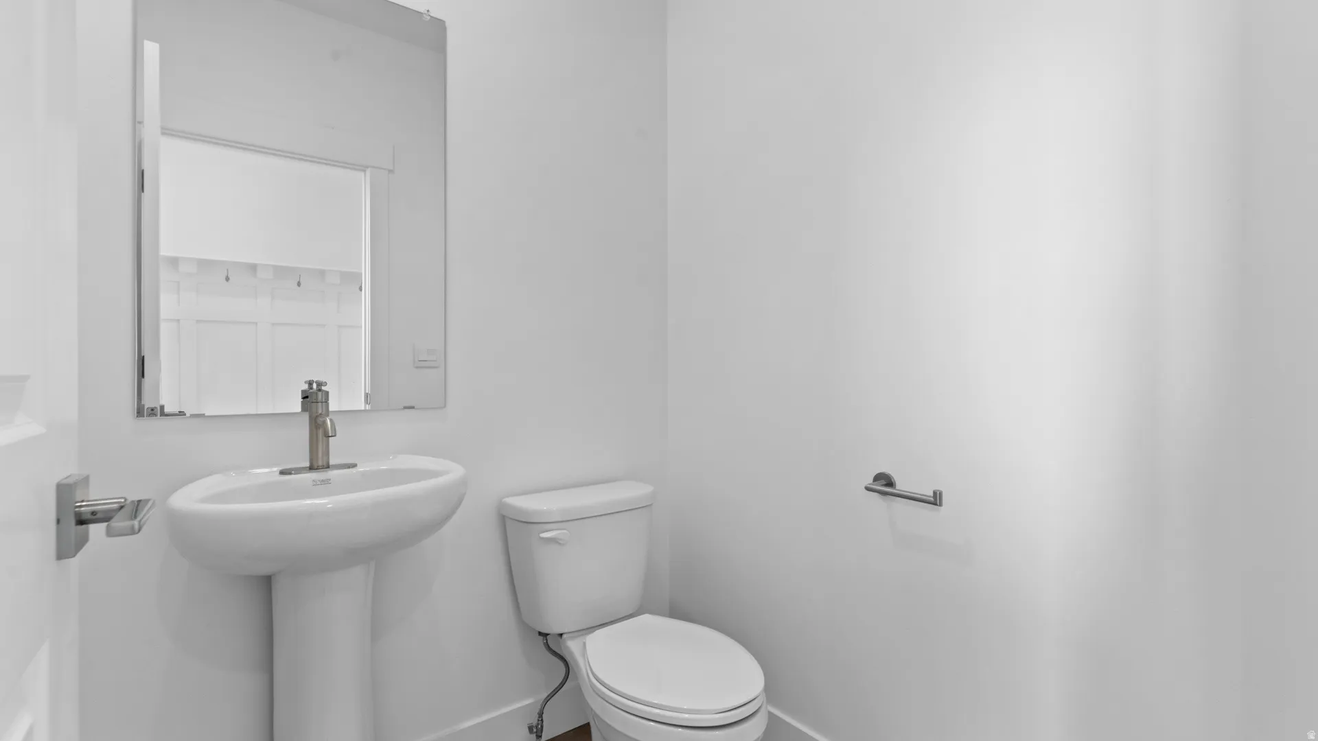 Pedestal sink with a contemporary brushed nickel faucet and a rectangular mirror