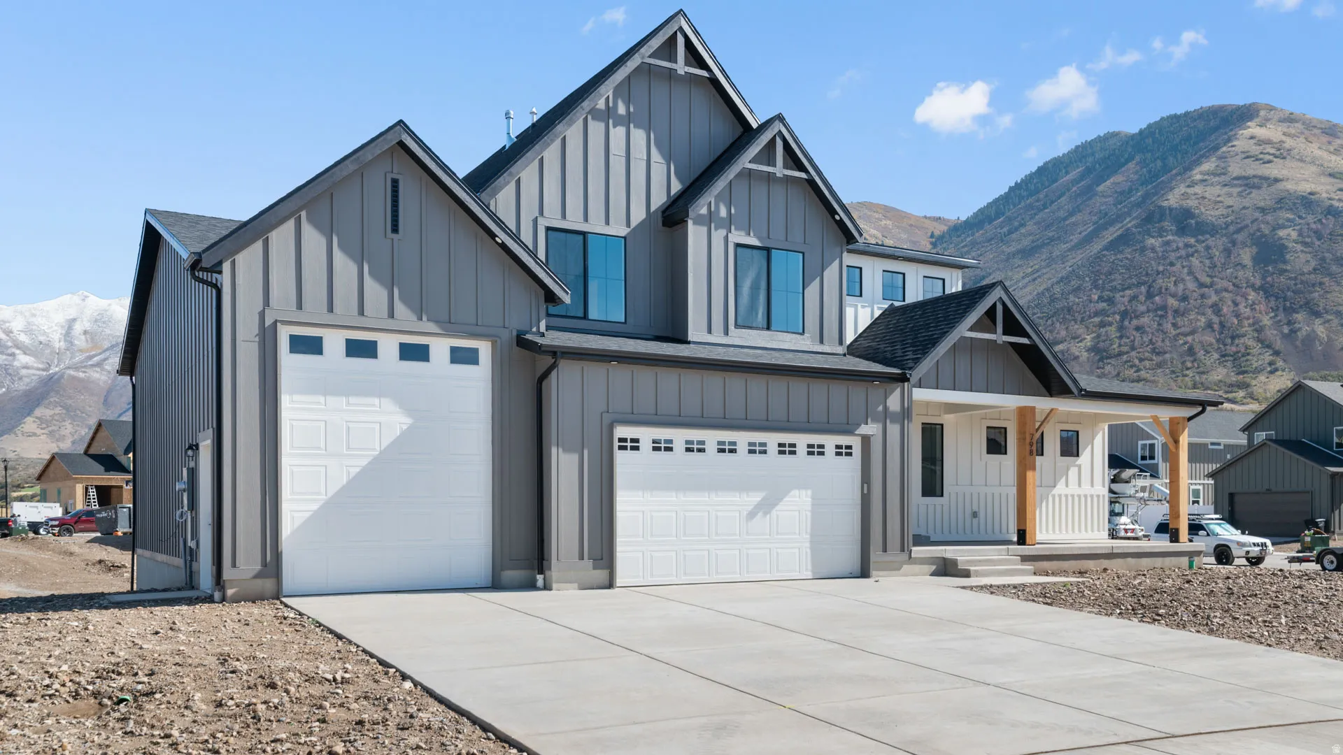 Modern farmhouse architecture featuring board and batten siding, multiple gables, and a prominent covered porch with natural wood posts