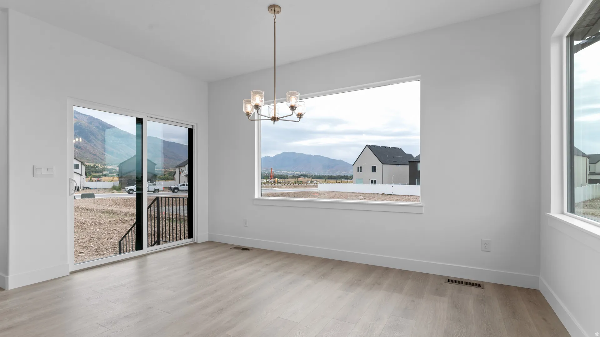Open living space featuring wood-finish flooring, a contemporary chandelier, and white wall finishes