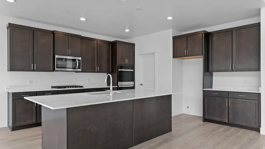 Contemporary kitchen featuring dark wood-finish cabinetry, light stone countertops, and wood-finish flooring
