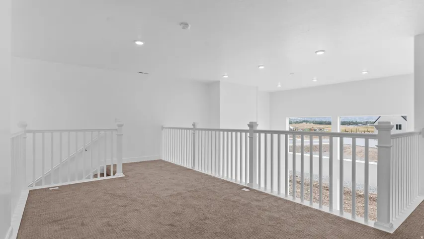 Expansive open loft area featuring plush brown carpeting and white railing