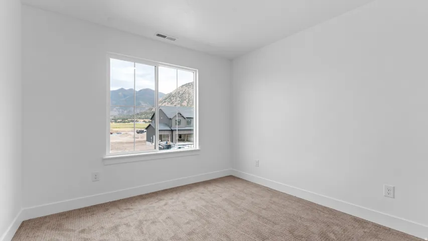 Bright interior space featuring a large window, neutral wall paint, white trim, and a textured carpet