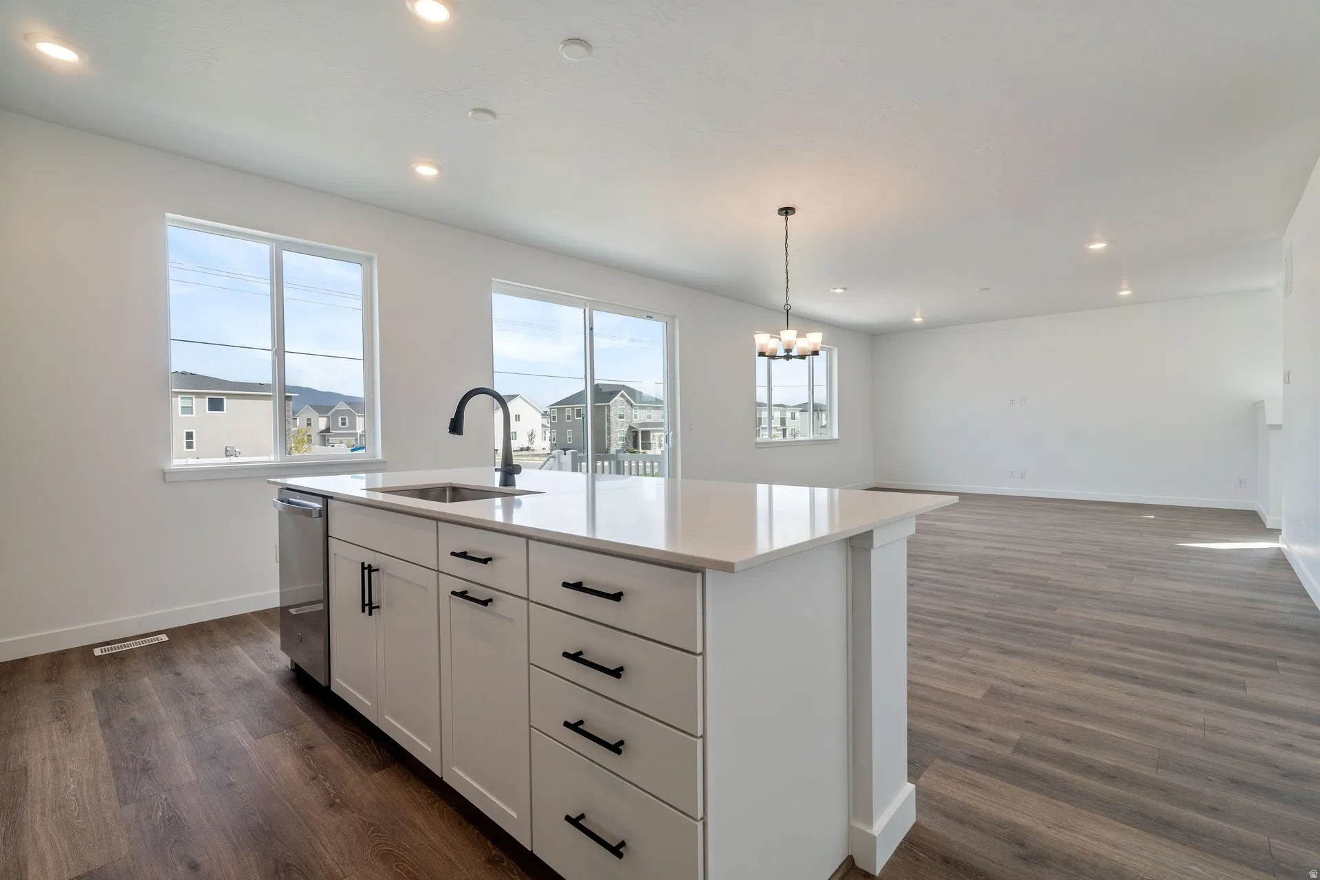 Kitchen island with a stainless steel sink, black faucet, and white countertop