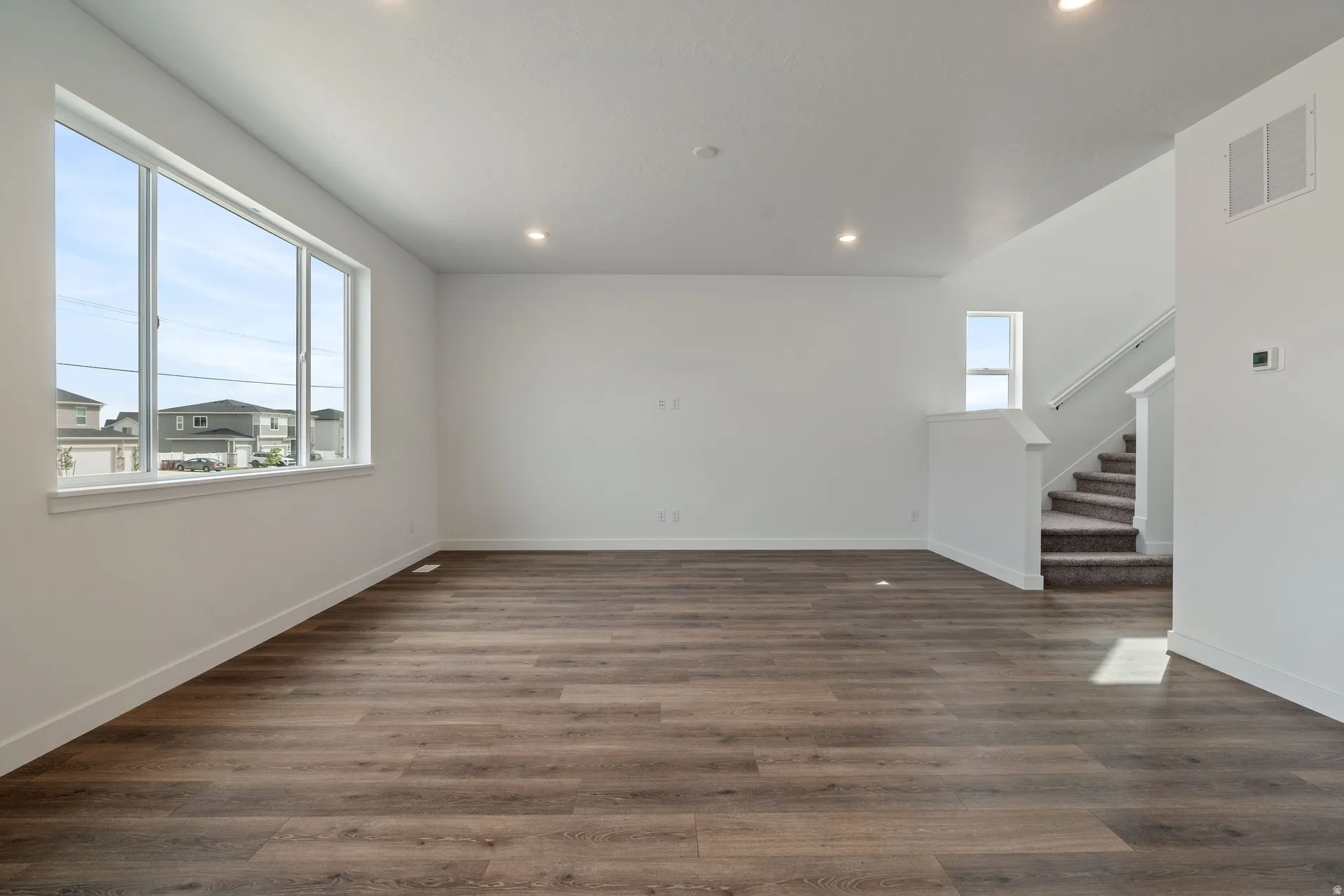 Expansive room featuring wood-finish flooring, white walls, and recessed lighting