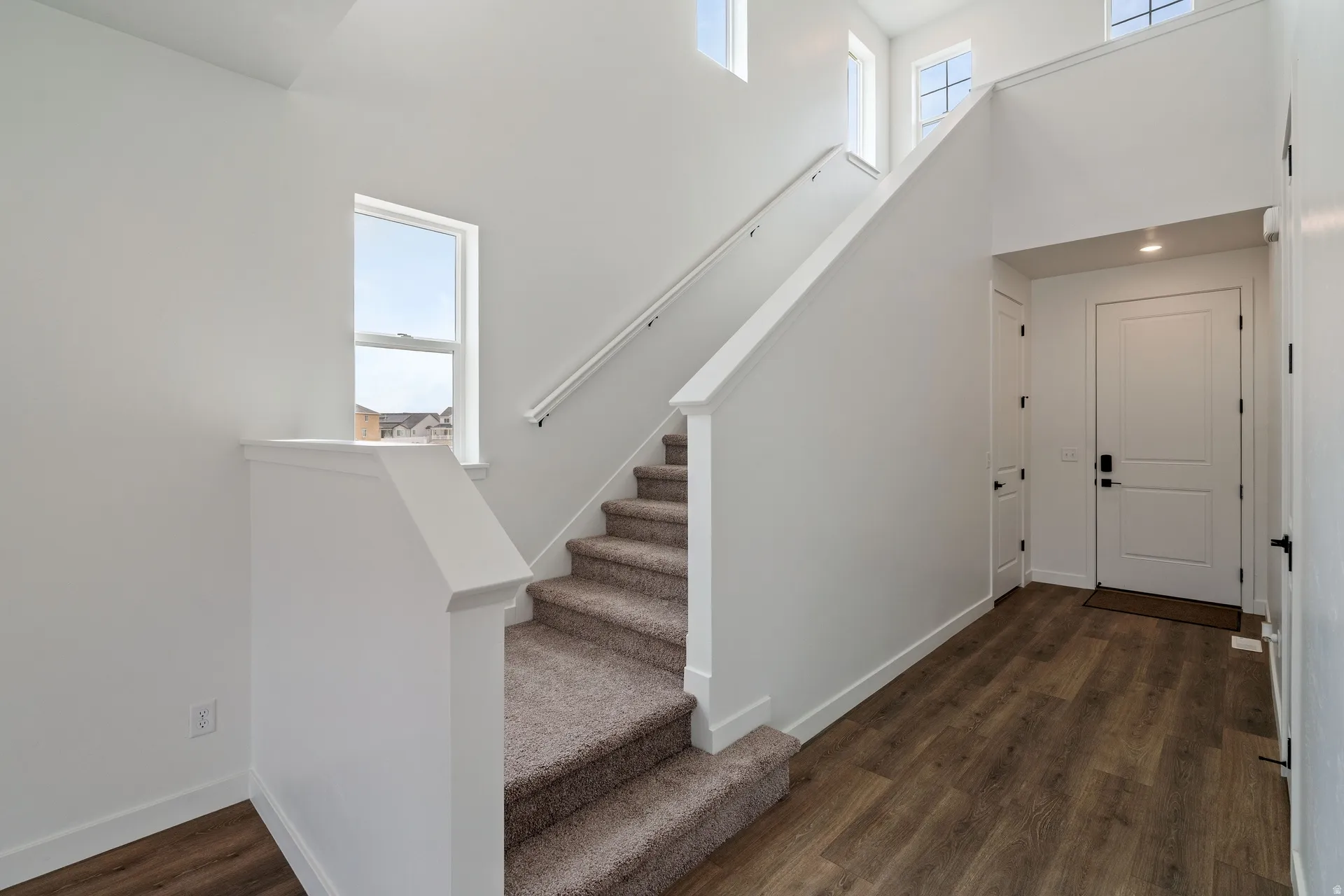 Entryway featuring an architectural staircase with carpeted treads and a white handrail