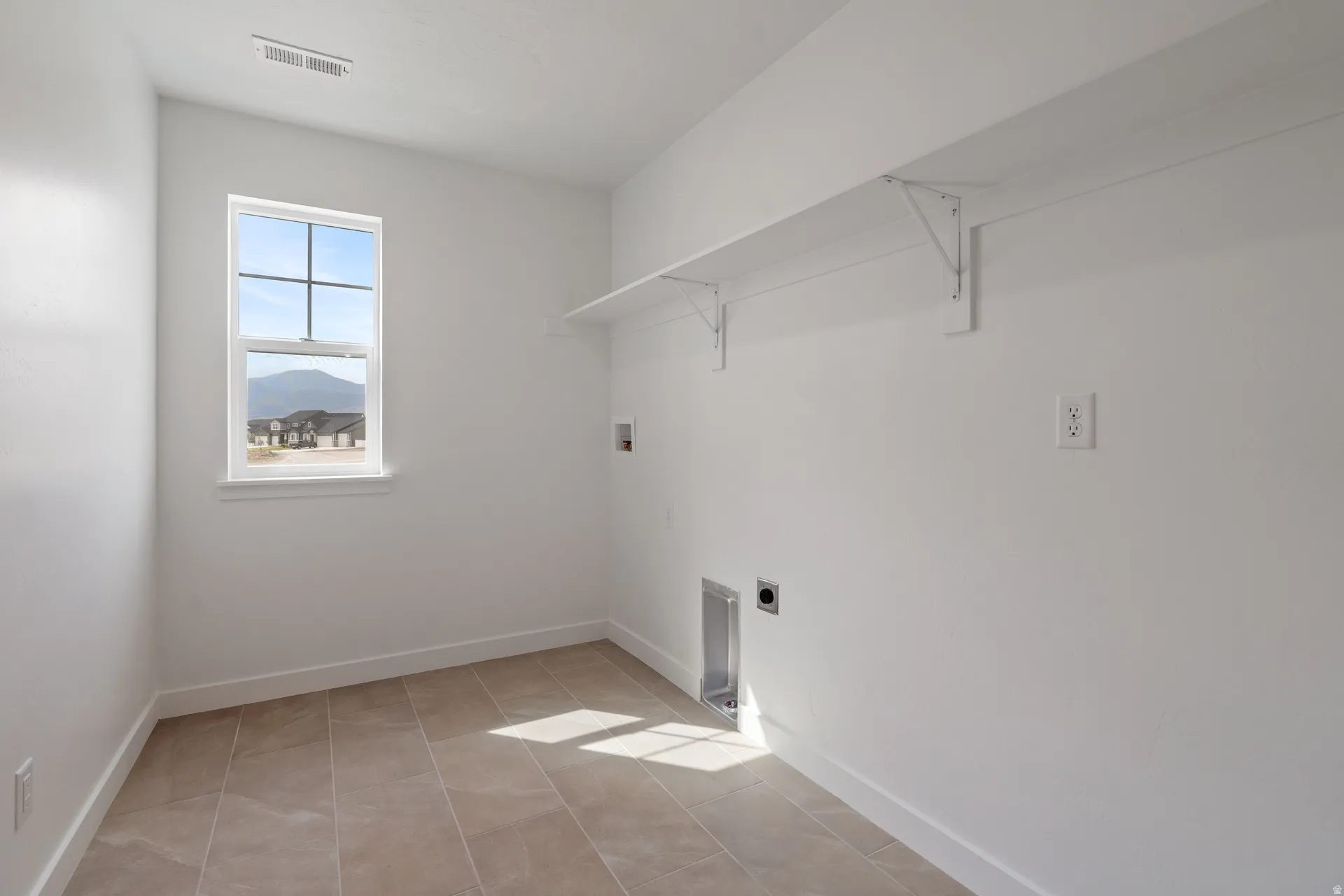 Utility room featuring light-colored tile flooring, white walls, and a window with mountain scenery
