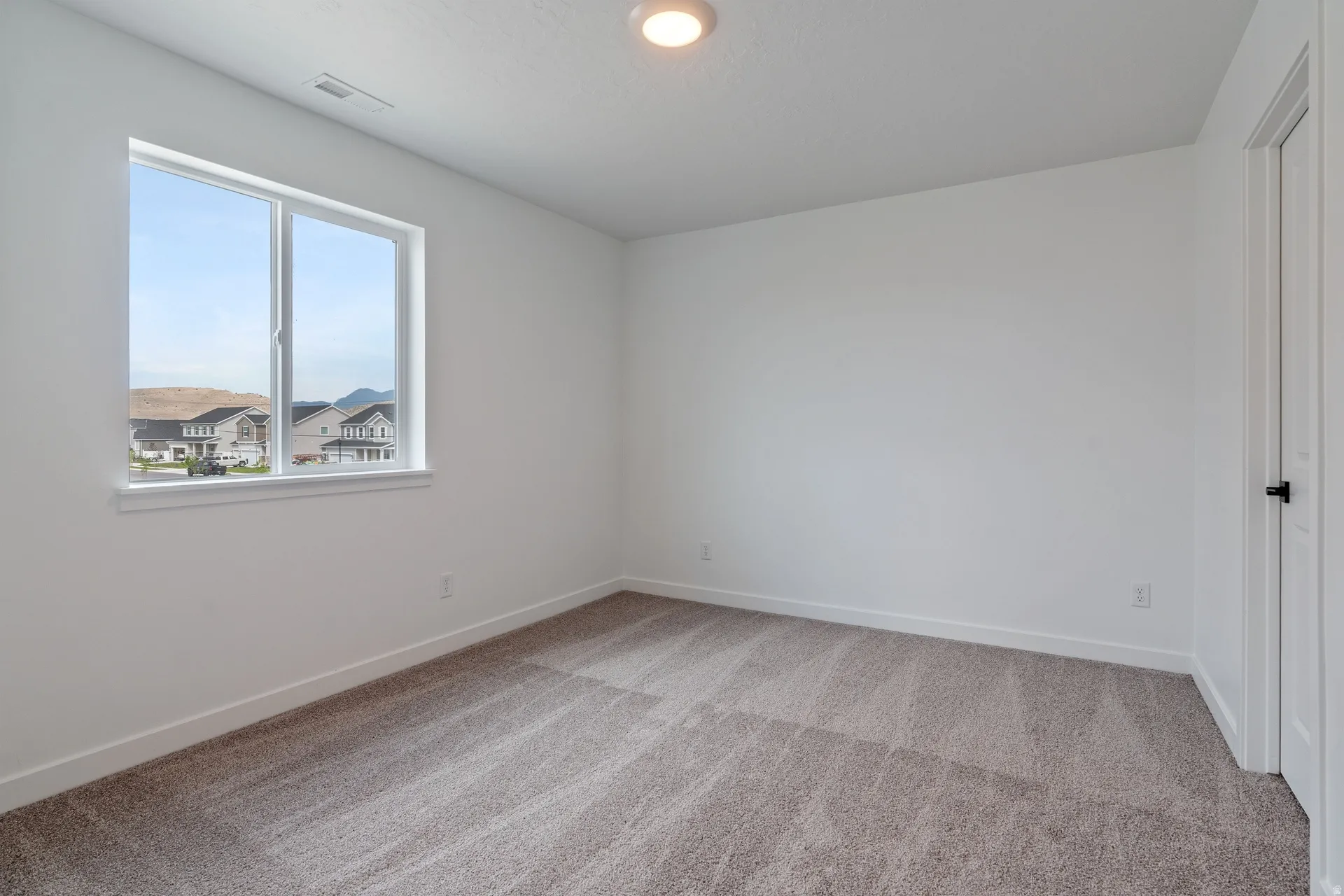 Bright room with light gray carpet, white walls, and a large window