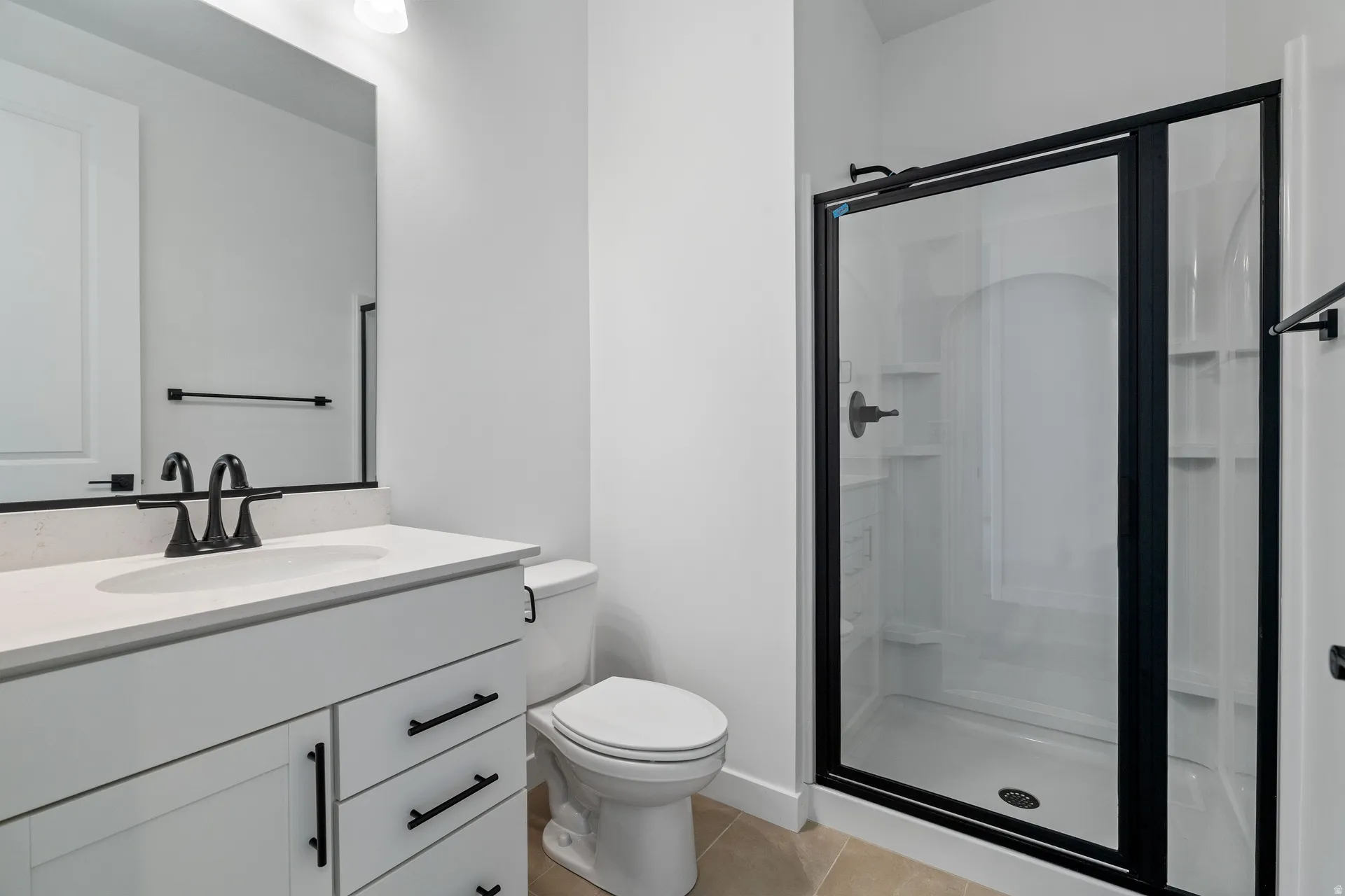 White vanity with a light-toned countertop, matte black hardware, and an undermount sink