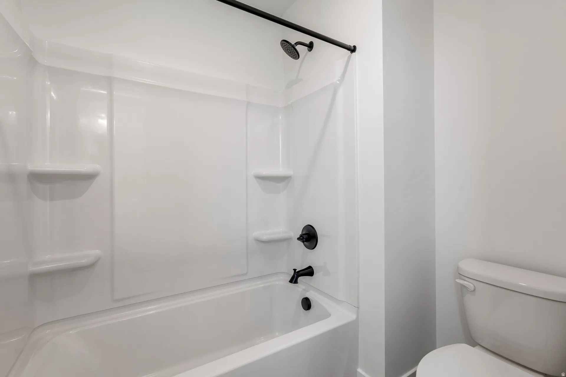 White fiberglass tub and shower combination featuring integrated shelving