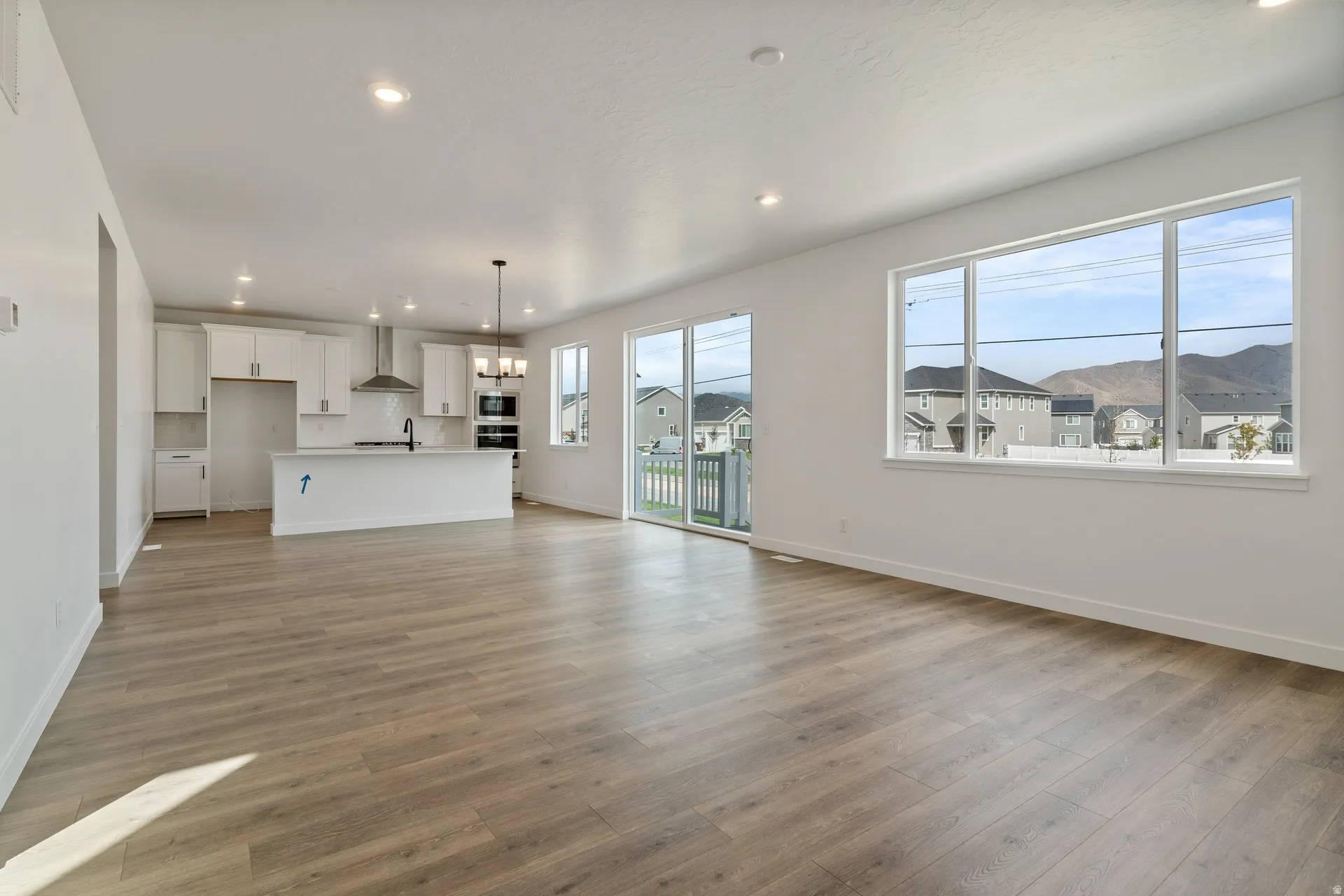 Open-concept living space featuring wood-finish flooring, recessed lighting, and a white kitchen with a central island