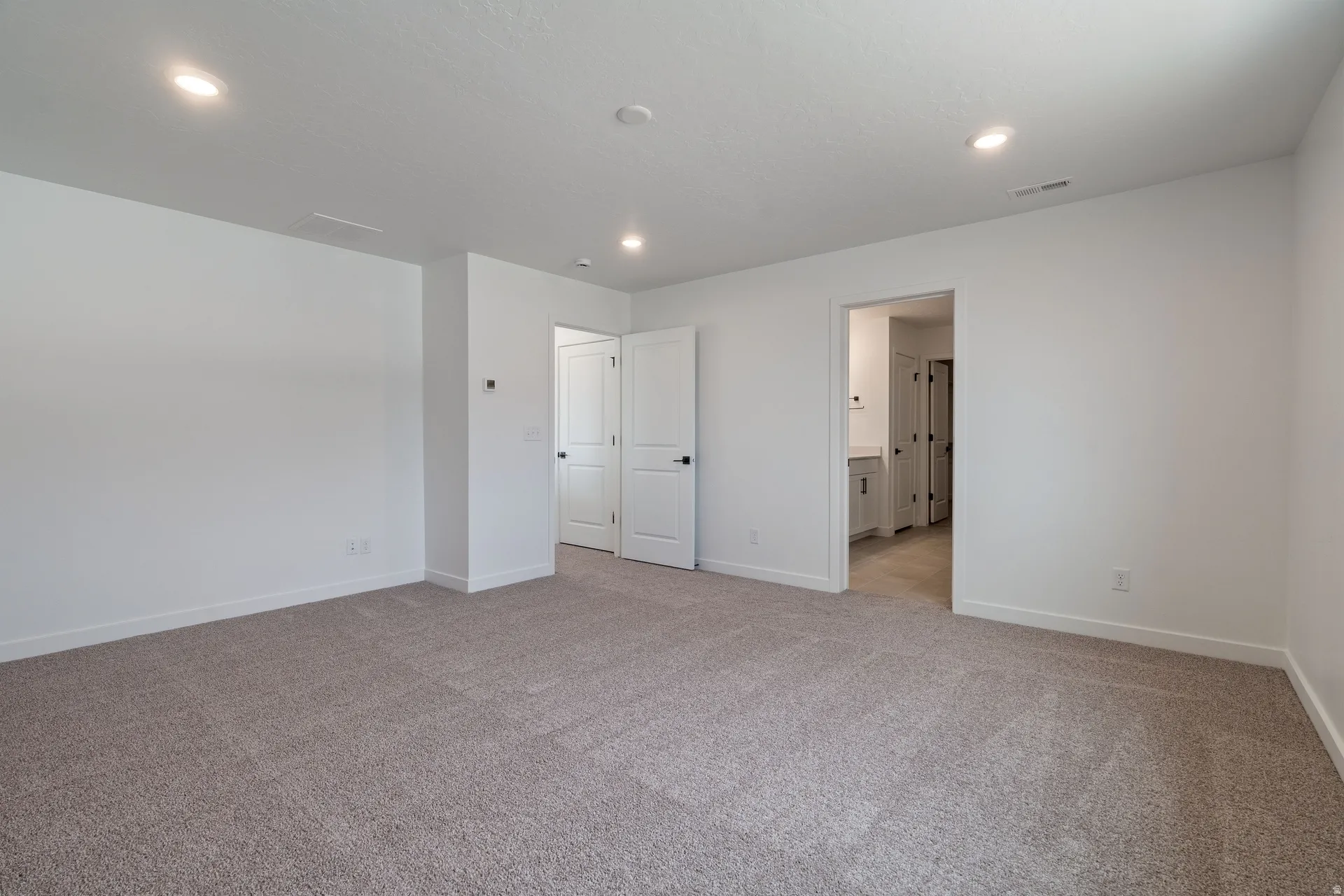 Neutral-toned carpeted room with recessed lighting