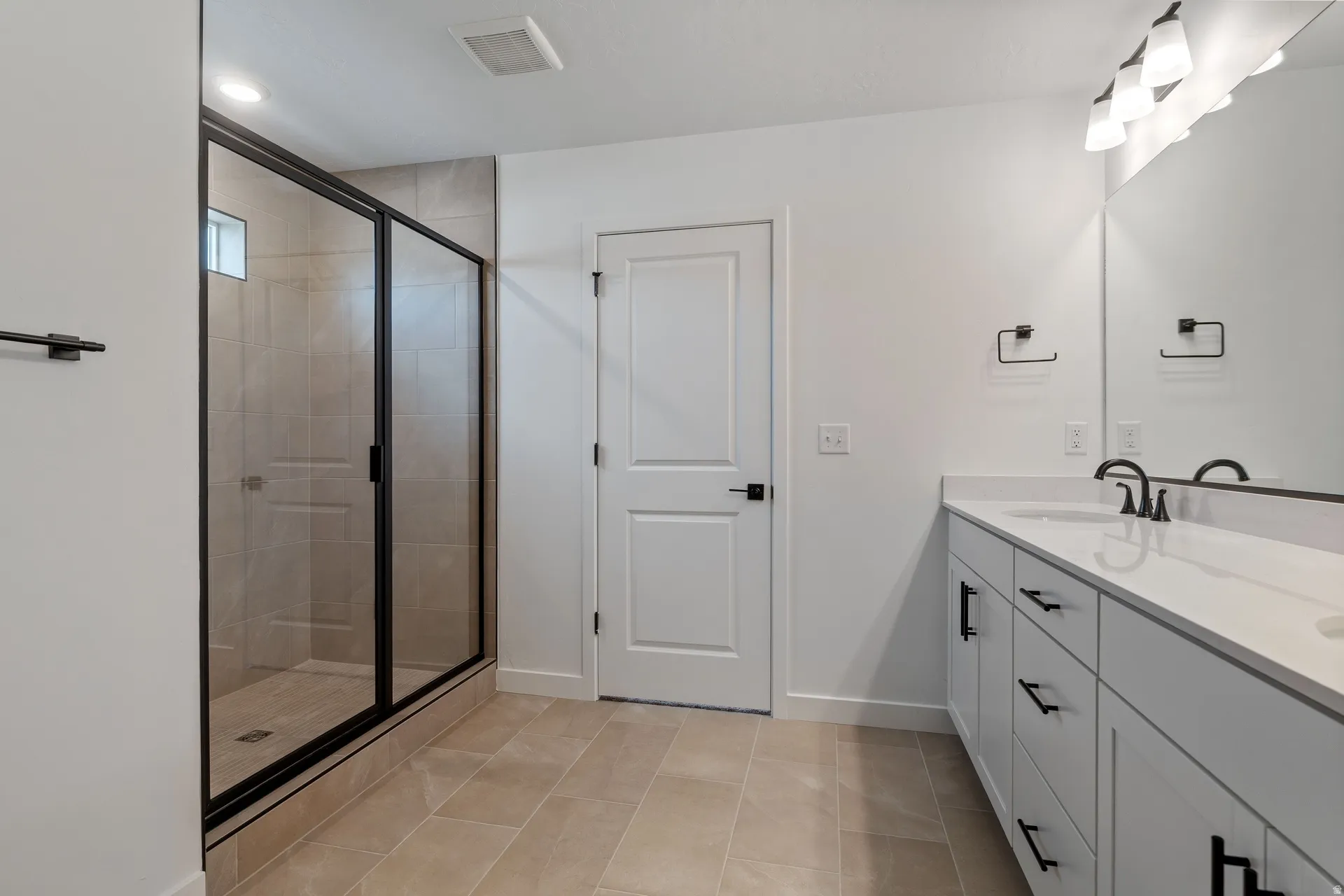Modern bathroom featuring a double vanity with white cabinetry, quartz countertops, and matte black fixtures