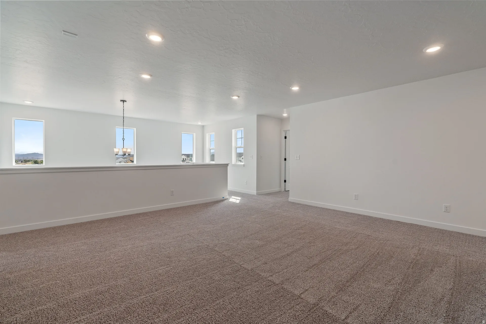 Spacious upper-level area with neutral-toned carpet and recessed lighting